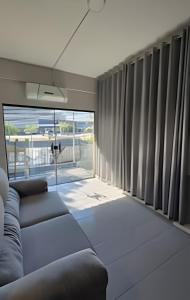 a living room with a couch and a large window at Vila Jaú Coliving Apartamentos e Studios - Djalma Batista in Manaus