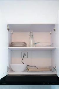 a kitchen shelf with plates and dishes on it at L'écrin rose, appartement coeur de ville de Bergerac in Bergerac