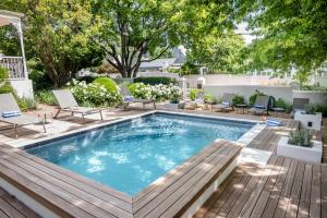 a swimming pool with a wooden deck and chairs around it at Corner House Residence in Franschhoek