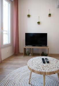 a living room with a table in front of a tv at L'écrin rose, appartement coeur de ville de Bergerac in Bergerac