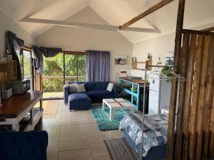 a living room with a blue couch and a table at Blue Lagoon 4x4 Cottage in Umngazana