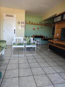 un soggiorno con sedie e una TV su un pavimento piastrellato di Apartamento a Luis Correia