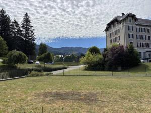 a building in a park with a grass field and a building at Appartement au cœur de Villard de Lans avec grande terrasse et double garage - FR-1-548-47 in Villard-de-Lans