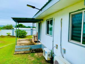 a white house with a porch and a window at Pedro's Hideaway in Mangilao