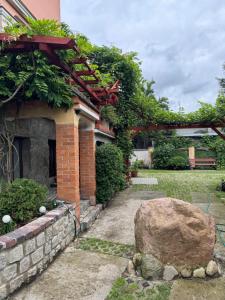 a brick house with a rock in the yard at Pokoje pod winogronami in Płoty