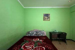a green room with a bed and a desk and a bed sidx sidx sidx at OYO 94714 Khayla Homestay Syariah in Yogyakarta