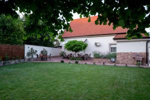 a garden with a table and chairs in a yard at Kollar D Guest House - Prenoćište ROOMS in Subotica