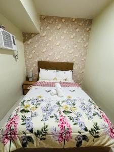 a bedroom with a bed with a floral bedspread at Brenthill Condominium in Baguio