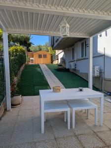 a white picnic table under a white pergola at Stella Apartment in Marina Palmense