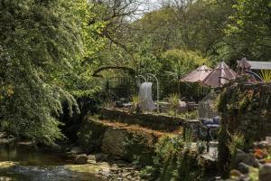a garden with a river and a table and chairs at The Old Mill House in Padstow