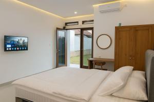 ein Schlafzimmer mit einem Bett und einem Fernseher an der Wand in der Unterkunft Casa Nika Kerobokan in Kerobokan