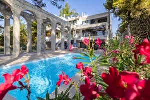 - une piscine en face d'une maison ornée de fleurs rouges dans l'établissement Pefka Luxury Homes, à Kalivia Poligirou