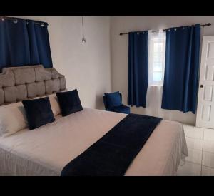 a bedroom with a large bed with blue curtains at Holiday Oasis in Ocho Rios