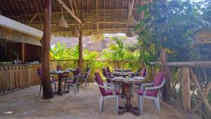 une terrasse avec tables et chaises dans un restaurant dans l'établissement Bush Paradise Kiwengwa, à Kiwengwa