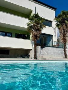 a house with palm trees in front of a swimming pool at Villa Vincek in Mostar