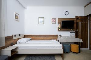 a bedroom with a bed and a desk and a tv at Kollar D Guest House - Prenoćište ROOMS in Subotica