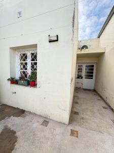 a white building with a window and potted plants at Casa verde in Cañada Rosquín +6 photos