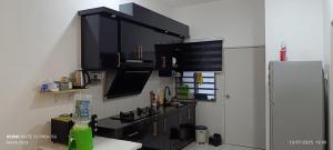 - une cuisine avec des armoires noires et un réfrigérateur dans l'établissement MAFA d' HOMESTAY, à Kuantan