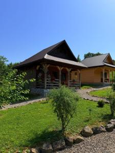 a house with a porch and a yard at Casa de la ferma Mariuca in Berbeşti