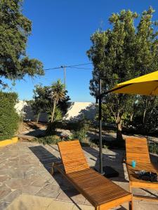 two wooden chairs and an umbrella on a patio at Casa dos Sobreiros in Palmela +50 photos