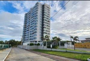 a tall white building with palm trees in front of it at Apto ALTO LUXO Atalaia - frente mar - Aracaju in Santa Maria