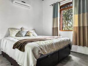 a bedroom with a large bed with a window at Refúgio Natureza Piscina Sala de Jogos Lazer in Campo Limpo Paulista
