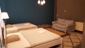 a room with two beds and a chair and a chandelier at Cozy Central Retreat in Budapest