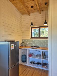 a kitchen with a refrigerator and two pendant lights at Casa Coguil - Camino Topocalma in Los Quillayes