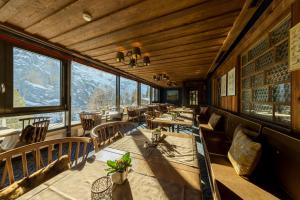 a restaurant with tables and chairs and large windows at Eiger Mürren Swiss Quality Hotel in Mürren