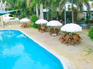 狄力的住宿－帝汶酒店，一组桌椅,在游泳池旁边配有遮阳伞