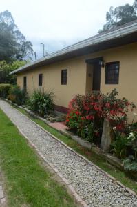 a house with red flowers in front of it at Mi casa amarilla in El Rosal