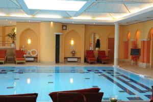 a large swimming pool in a building with red chairs at Steigenberger Hotel & Spa Bad Pyrmont in Bad Pyrmont