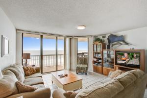 a living room with a couch and a tv at Charleston Oceanfront Villas 311 in Folly Beach