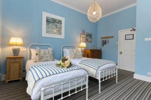 two beds in a bedroom with blue walls at Dolphin Hotel in Beer