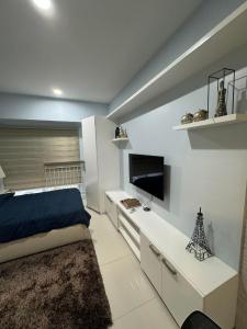 une chambre avec un lit et un bureau avec une télévision dans l'établissement SMDC wind residences, à Kaybagal