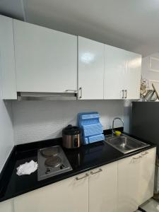 La cuisine est équipée de placards blancs, d'une cuisinière et d'un évier. dans l'établissement SMDC wind residences, à Kaybagal