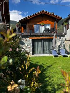 a house with two chairs and an umbrella in a yard at Casa Borna da Ghiasa in Emarese