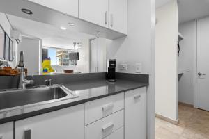 Una cocina con gabinetes blancos y un fregadero. en Otium Pool Beach Access, en San Juan