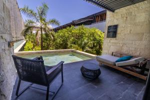 a patio with a chair and a swimming pool at Devossion By Live Aqua Playa del Carmen All Inclusive - Adults Only in Playa del Carmen