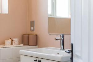 a bathroom with a white sink and a mirror at Pebble Cove by Keepers Cottages in Walmer +29 photos