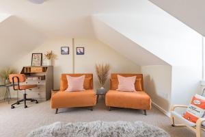 an attic room with two orange chairs and a desk at Pebble Cove by Keepers Cottages in Walmer
