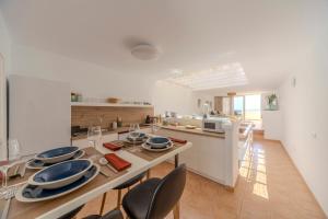 a white kitchen with a table and chairs and a counter at Luxury Colony Club Sea Views in Tías
