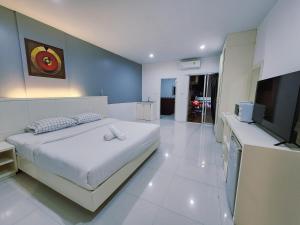 Un dormitorio con una gran cama blanca y un televisor de pantalla plana. en ALBADER HoTEL, en Patong Beach