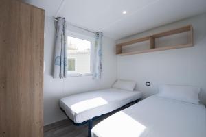 two beds in a small room with a window at Camping Aux Rives du Soleil in Pont-de-Vaux +40 photos