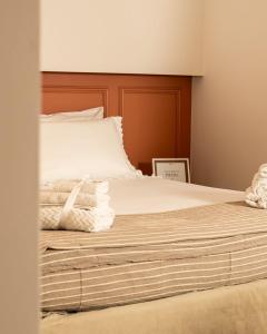 a bed with white sheets and a wooden headboard at La Casetta di Giadapia - Apulia Houses & Flats in Ruvo di Puglia