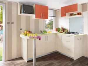 a kitchen with white cabinets and a table with fruit on it at Mobil Home Confort 2 Chambres avec Terrasse - API-1-52-347 in Rives