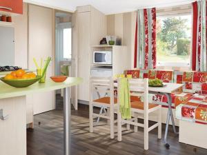 a kitchen and dining room with a table and chairs at Mobil Home Confort 2 Chambres avec Terrasse - API-1-52-347 in Rives