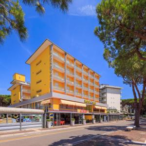 een geel gebouw in een stadsstraat met bomen bij Hotel Sole in Rosolina Mare