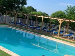 ein Swimmingpool mit blauen Stühlen und einer hölzernen Pergola in der Unterkunft Mobil home confortable 6 personnes à Limeuil - API-1-52-281 in Limeuil + 7 Fotos