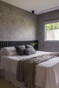 a bedroom with a large white bed with a window at Vila Piá 02 in Piaçabuçu